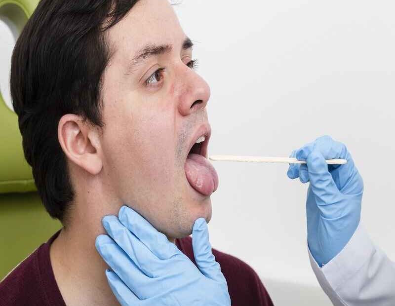 Doctor examining a patient's throat with a tongue depressor during a check-up.