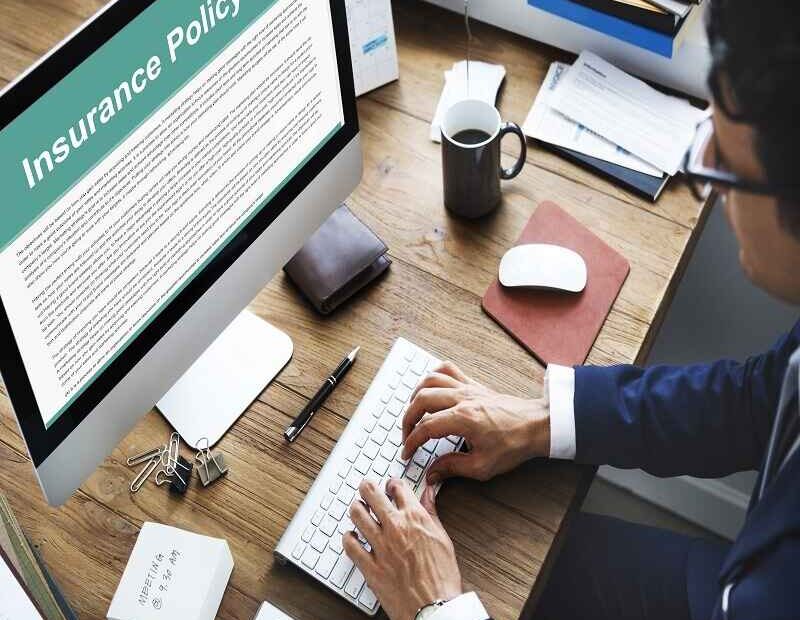 Person reviewing an insurance policy document on a computer screen at a desk, illustrating insurance planning and documentation.