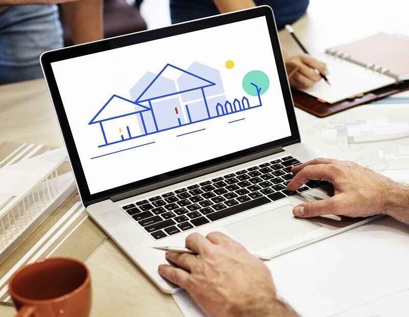 Person using a laptop displaying a graphic of houses, representing property management services.